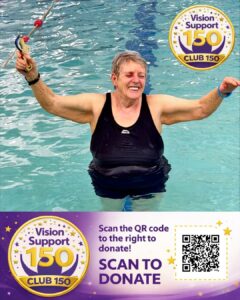 Jean smiles in a swimming pool with her arms raised, holding goggles. She wears a black swimsuit and stands in clear blue water. In the top corner is the Vision Support Club 150 badge, a gold-rimmed circular logo with stars and “Vision Support 150” and a “CLUB 150” ribbon. Text below reads: “Scan the QR code to the right to donate! SCAN TO DONATE”, with a QR code on the right.